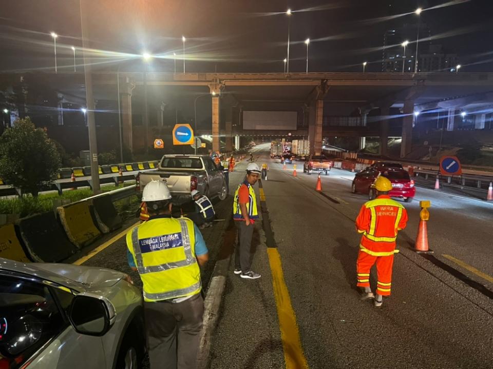 Workers blackening and repainting overlapping lane markings on DASH expressway to ensure consistency. — Picture courtesy of Works Ministry