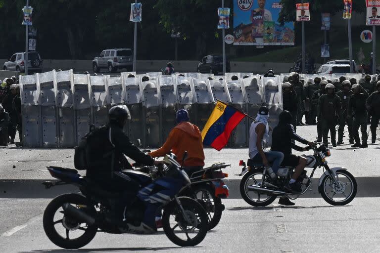 Los manifestantes en motos frente a miembros de la Guardia Nacional Bolivariana en Caracas.