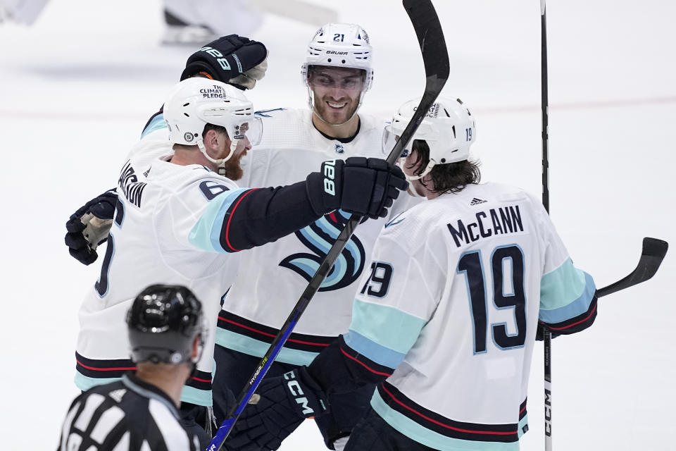 Seattle Kraken defenseman Adam Larsson (6), left wing Jared McCann (19) and center Alex Wennberg (21) celebrate after Larsson scored in overtime of an NHL hockey game against the Dallas Stars, Tuesday, March 21, 2023, in Dallas. The Kraken won 5-4. (AP Photo/Tony Gutierrez)