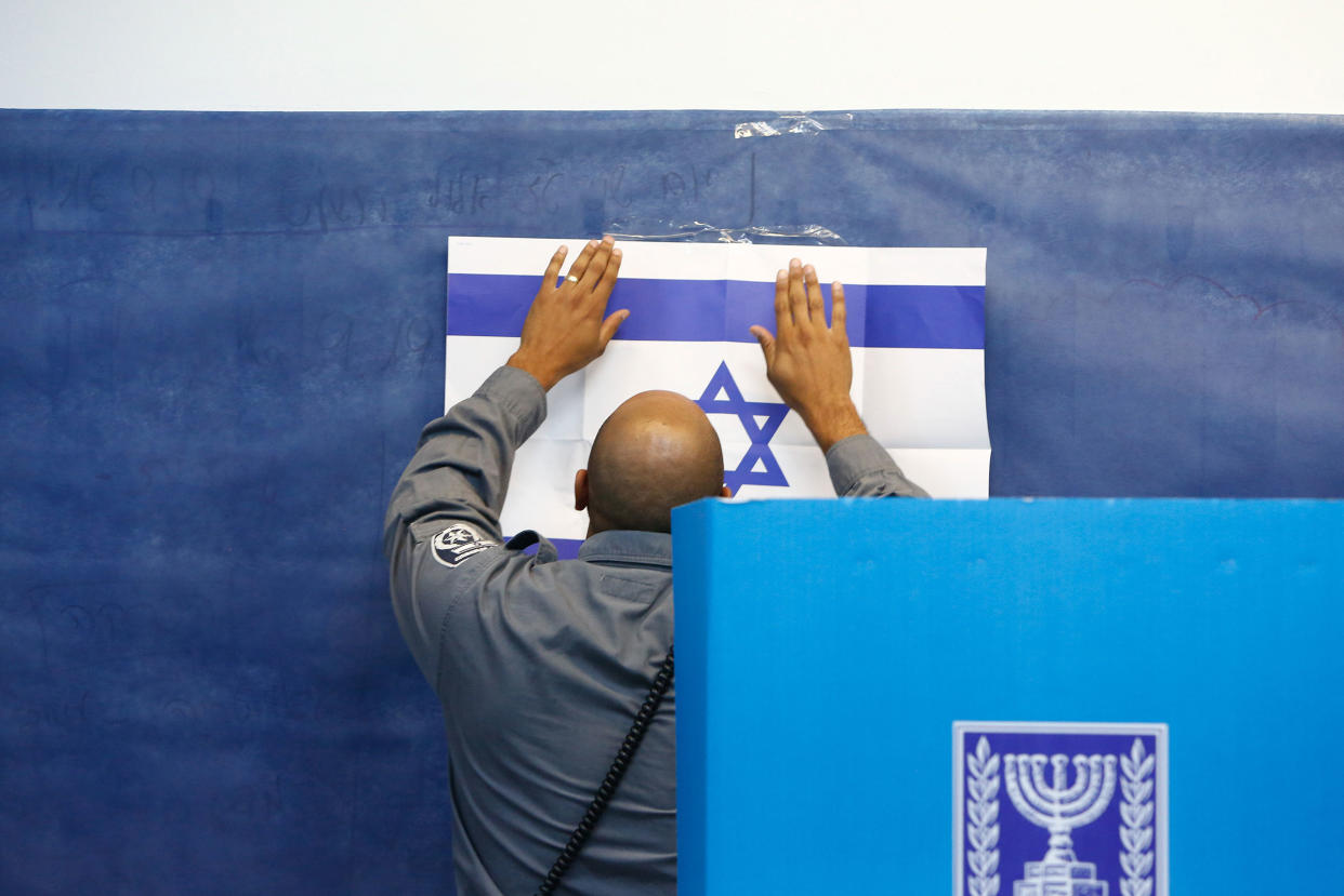 An official adjusts a poster of the Israeli flag at a polling station in Rosh Haayin, Israel, on Sept. 17, 2019.