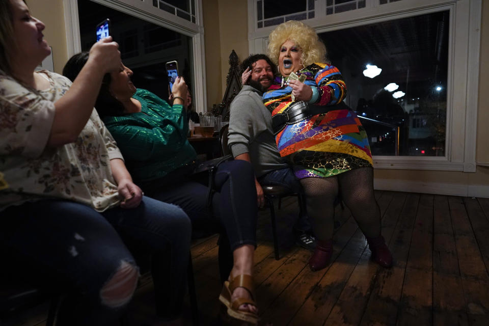 Drag queen Alexus Daniels lip-syncs to "Heart of Glass" by Blondie as she sits on the lap of a smiling and consenting audience member and others take photos during the "Daniels Family Values" drag show at the Heritage Restaurant in Shamokin, Pa., Saturday, April 16, 2022. Daniels, the drag family matriarch, was the child of a coal miner and textile worker who was "born with a female spirit." She works at the local hospital as an MRI aide tech. (AP Photo/Carolyn Kaster)