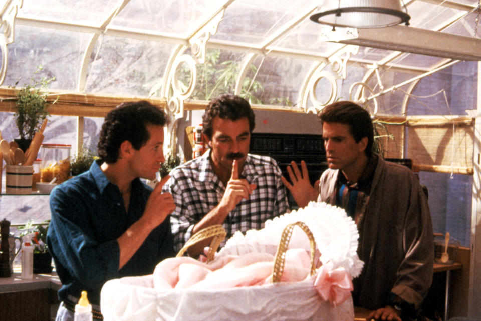 Steve Guttenberg, Tom Selleck, and Ted Danson huddle around a baby