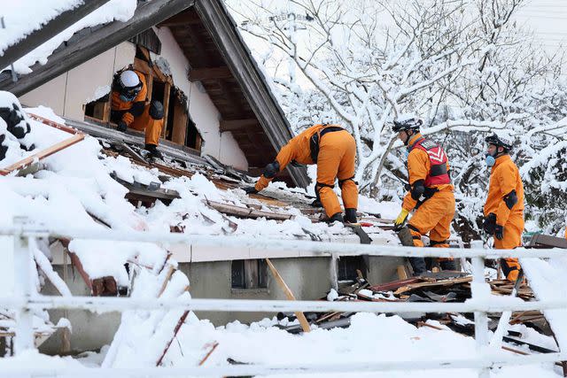 <p>STR/JIJI Press/AFP via Getty</p> Firefighters search for survivers in snow-covered ruins in the city of Suzu, Ishikawa prefecture on Jan. 8, 2024, a week after a major 7.5 magnitude earthquake struck the Noto region