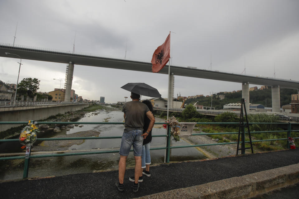 A couple looks at the new San Giorgio Bridge ahead of its inauguration in Genoa, Italy, Monday, Aug. 3, 2020. A large section of the old Morandi bridge collapsed on Aug. 14, 2018, killing 43 people and forcing the evacuation of nearby residents from the densely built-up area. (AP Photo/Luca Bruno)