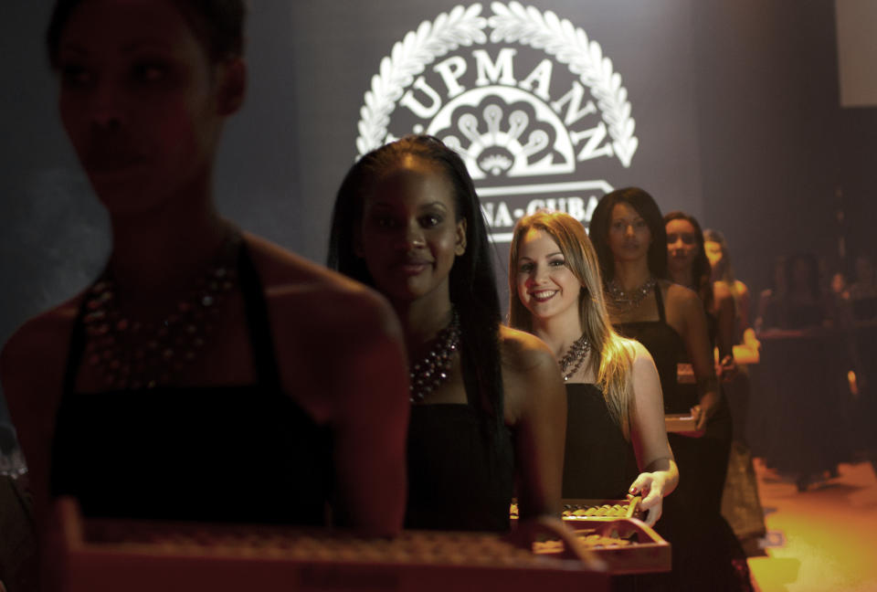 Cuban models carry cigars during a gala dinner marking the end of the 16th annual Cigar Festival in Havana, Cuba, Friday, Feb. 28, 2014. Cigar aficionados have paid more than €798,000 ($1.1 million) for six handmade Cuban humidors at the gala closing of Havana's 16th annual Cigar Festival, a five-day bash that brings together hundreds of cigar sophisticates from around the world. The hot item was a one-of-a-kind handcrafted humidor packed with Montecristo cigars that fetched €170,000 ($235,000).(AP Photo/Franklin Reyes)