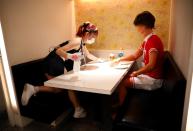 A waitress cleans a table with alcohol as a mannequin wearing cheerleader-outfit is placed for social distancing amid the coronavirus disease (COVID-19) outbreak at the cheerleader-themed restaurant 'Cheers One' in Tokyo