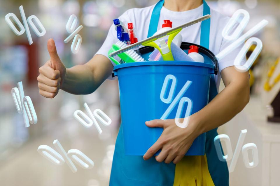 A cleaner gives a thumbs up while holding a bucket of cleaning products.