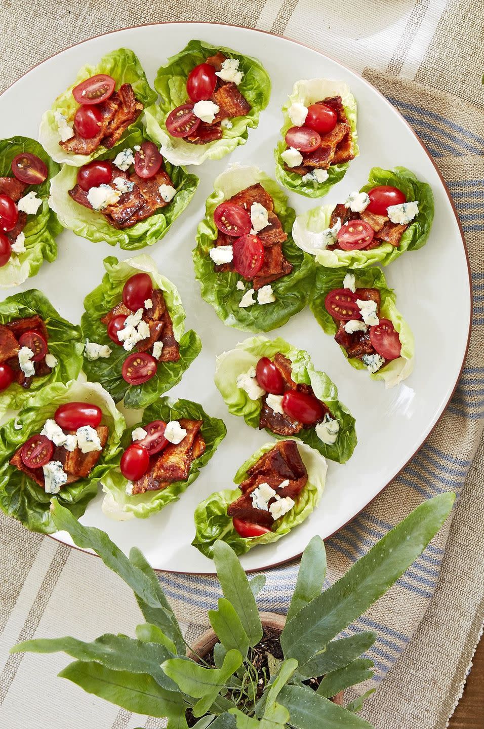 bacon lettuce cups with grape tomatoes and crumbled blue cheese arrange on a white plate