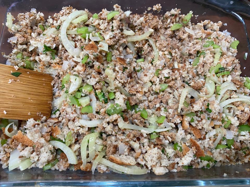Mixing the stuffing with veggies and broth in glass baking dish to make Sunny Anderson's stuffing