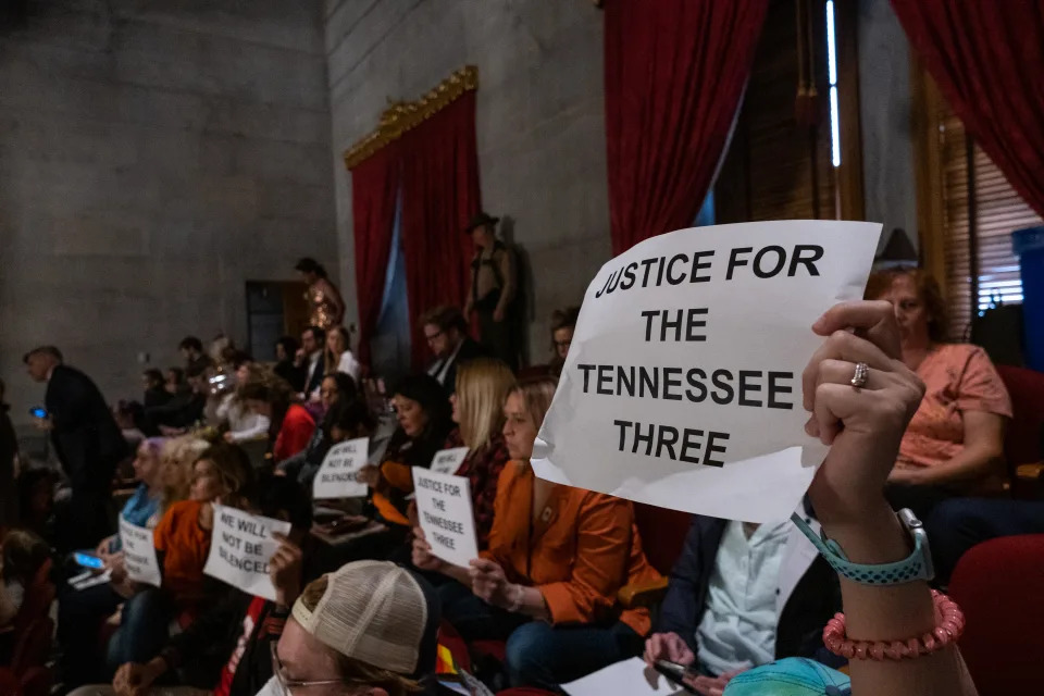 Protesters the gallery hold signs saying: Justice for the Tennessee Three and We Will Not Be Silenced.