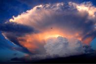 A jet plane flies past a mushroom-like cumulonimbus storm cloud in Beijing, China (REX)