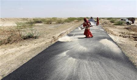 Women labourers throw dust on a road tarmac under construction at Bharadva village in the western Indian state of Gujarat April 23, 2013. REUTERS/Amit Dave