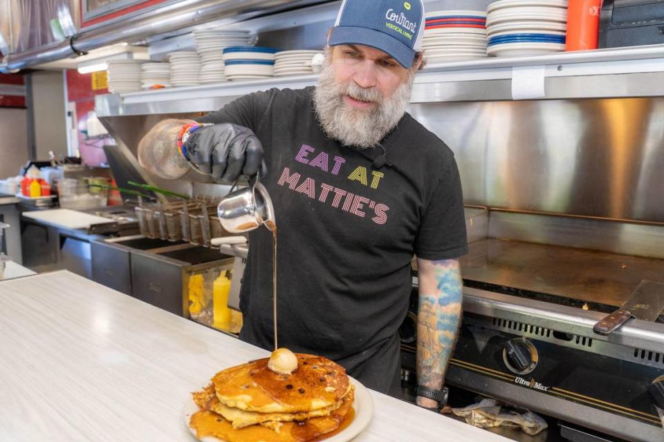 Matt King, owner of Mattie’s Diner, pours syrup over a stack of blueberry pancakes.