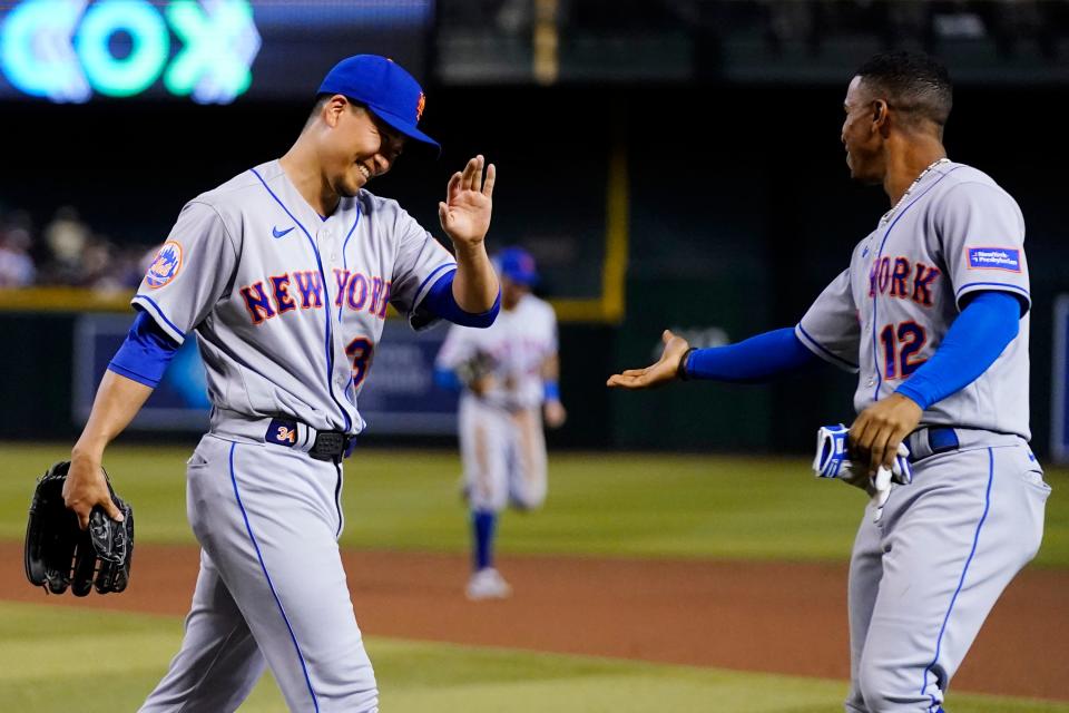 After Arizona Diamondbacks' Alek Thomas flew out, New York Mets starting pitcher Kodai Senga smiles as he slaps hands with shortstop Francisco Lindor (12) during the fifth inning of a baseball game Wednesday, July 5, 2023, in Phoenix.