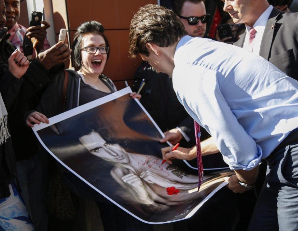 Prime Minister Justin Trudeau, right, signs a portrait of himself held by Kelly Archibald as he meets with students at the Southern Alberta Institute of Technology in Calgary, Alta., Tuesday, March 29, 2016. THE CANADIAN PRESS/Jeff McIntosh