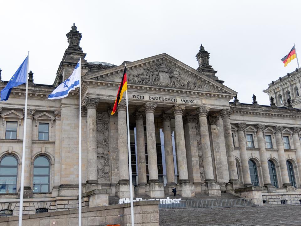 An Israeli flag flies next to a German flag and a European Union flag in front of the Reichstag building on January 26, 2022.