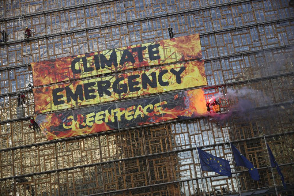 Climate activists climb next to a giant banner during a demonstration outside an EU summit meeting in Brussels, Thursday, Dec. 12, 2019. Greenpeace activists on Thursday scaled the European Union's new headquarters, unfurling a huge banner warning of a climate emergency hours before the bloc's leaders gather for a summit focused on plans to combat global warming.(AP Photo/Francisco Seco)