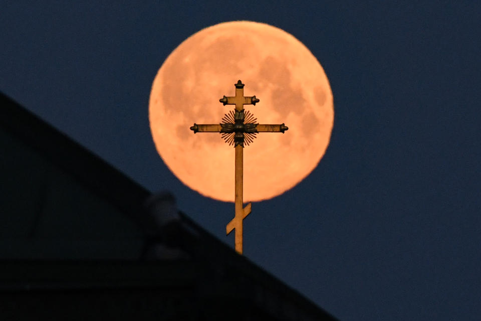 This picture taken early on April 8, 2020 shows the closest supermoon to the Earth, also known as a pink moon, behind the cross on a church in downtown Moscow. (Photo by KIRILL KUDRYAVTSEV/AFP via Getty Images)