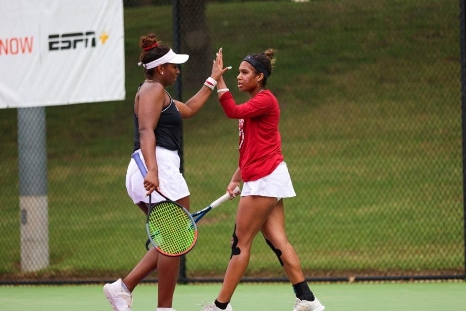 Ivana (left) and Carmen (right) Corley high-five each other after securing a point in a doubles match.