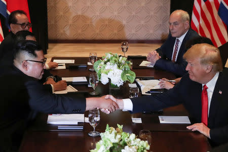 U.S. President Donald Trump and North Korea's leader Kim Jong Un shake hands during an expanded bilateral meeting at the Capella Hotel on the resort island of Sentosa, Singapore June 12, 2018. With them are Senior North Korean Diplomat Ri Su Yong (top L) and White House Chief of Staff John Kelly (top R). REUTERS/Jonathan Ernst