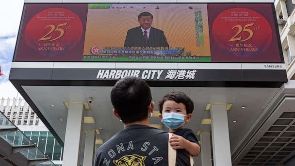 PHOTO: HONG KONG, CHINA: A man holding a child walks in front of a screen showing a live broadcast of Chinese President Xi Jinping speaking during a swearing-in ceremony for Hong Kong's new chief executive John Lee, on July 01, 2022 in Hong Kong, China.  (Anthony Kwan/Getty Images)