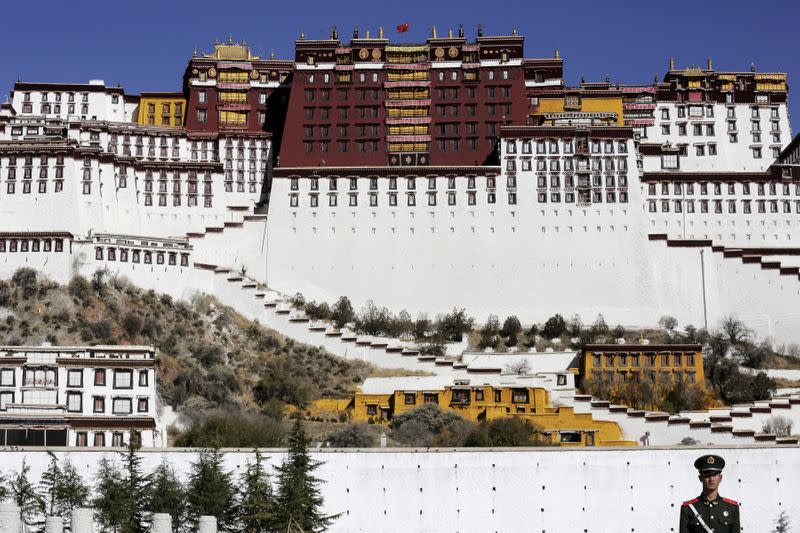 FILE PHOTO: A paramilitary policeman stands guard in front of the Potala Palace in Lhasa, Tibet Autonomous Region