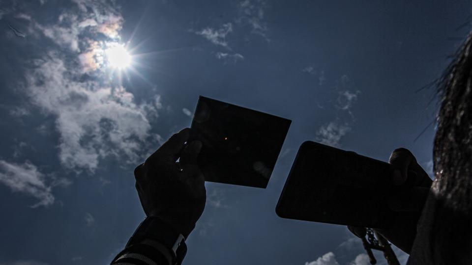 A man use protective mirror to watch solar eclipse in Palembang, Indonesia on April 20, 2023