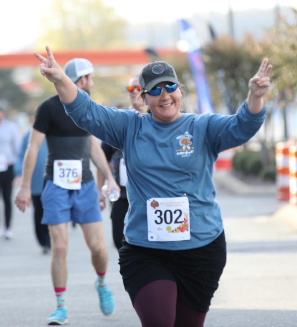 Heather Durham celebrates as she crosses the finish line during the 18th Annual Turkey Day 5K sponsored by Gold's Gym and Fleet Feet on Thursday, November 24, 2022, in Jackson, Tennessee.  Over 600 runners participate in the event each year which is held to benefit the Regional Inter-faith Association (RIFA).