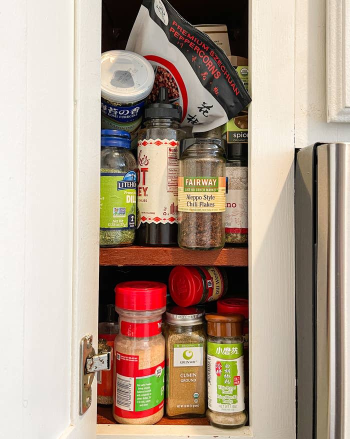 The author's messy spice cabinet, full of disorganized spices that are mostly full.