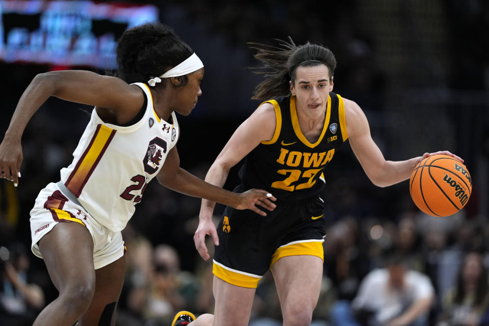 Iowa guard Caitlin Clark (22) drives up court past South Carolina guard Raven Johnson, left, during the first half of the Final Four college basketball championship game in the women's NCAA Tournament, Sunday, April 7, 2024, in Cleveland. (AP Photo/Carolyn Kaster)