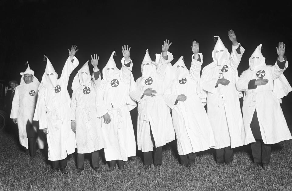 (Original Caption) Long Island, NY-Ku Klux Klan with hands raised in oath during night meeting.