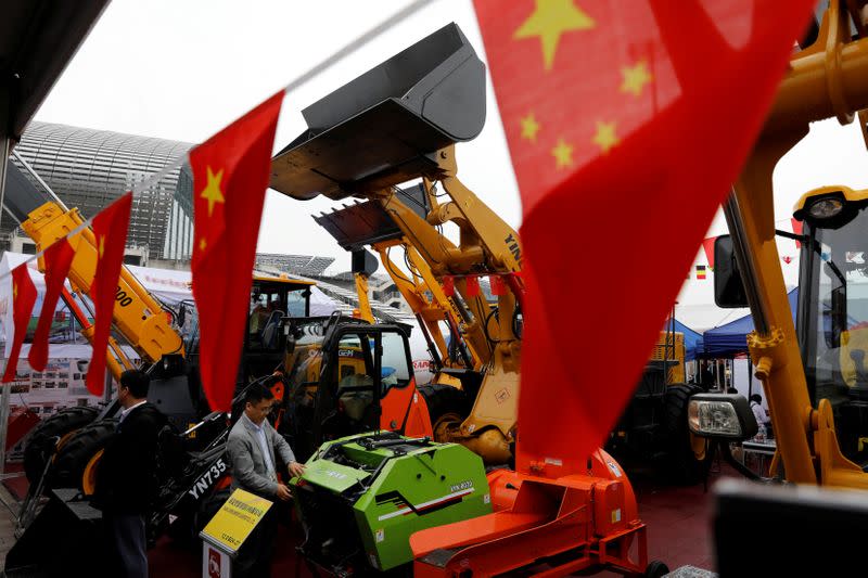 FILE PHOTO: Chinese flags are seen in front of construction vehicles during the China Import and Export Fair, also known as Canton Fair, in the southern city of Guangzhou