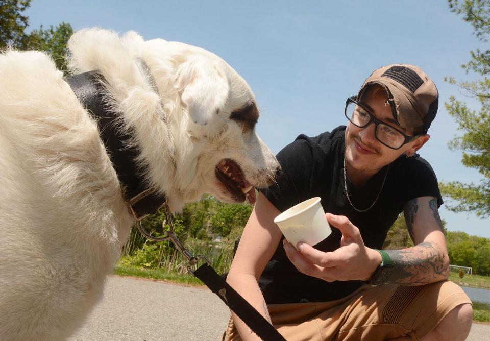 Kacey Kruzel of Pomfret bought his dog, named Bolt, a Puppy Bites ice cream treat at the grand opening of Ra Ra's Ice Cream Shop Friday at Owen Bell Park in Dayville. The warm weather business near the back parking lot at Owen Bell Park features soft and hard ice cream, ice cream cakes and birthday parties.