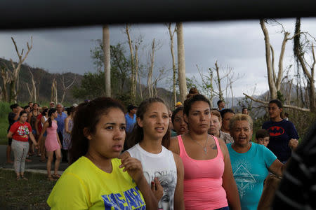 Residents stand in front of wind-damaged trees as they wait for soldiers in UH-60 Blackhawk helicopters from the First Armored Division's Combat Aviation Brigade to deliver food and water during recovery efforts following Hurricane Maria, in San Lorenzo, Puerto Rico, October 7, 2017. REUTERS/Lucas Jackson