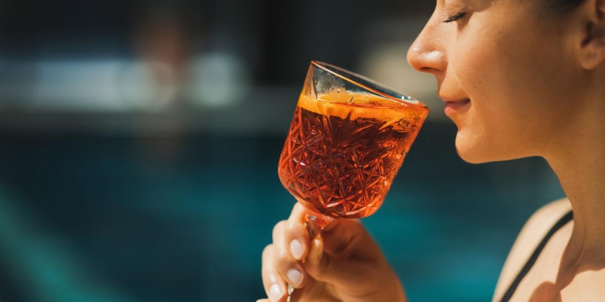 woman drinking aperol spritz by the pool