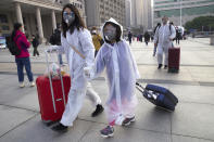 Passengers wearing face masks and rain coats to protect against the spread of new coronavirus walk outside of Hankou train station after of the resumption of train services in Wuhan in central China's Hubei Province, Wednesday, April 8, 2020. After 11 weeks of lockdown, the first train departed Wednesday morning from a re-opened Wuhan, the origin point for the coronavirus pandemic, as residents once again were allowed to travel in and out of the sprawling central Chinese city. (AP Photo/Ng Han Guan)