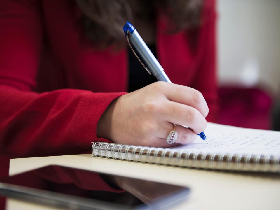 Note-taking on a pice of sheet with a pen during a business meeting.