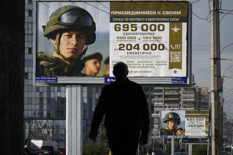 A man walks past advertising billboards which promote contract military service in the Russian army in St Petersburg, September 2023