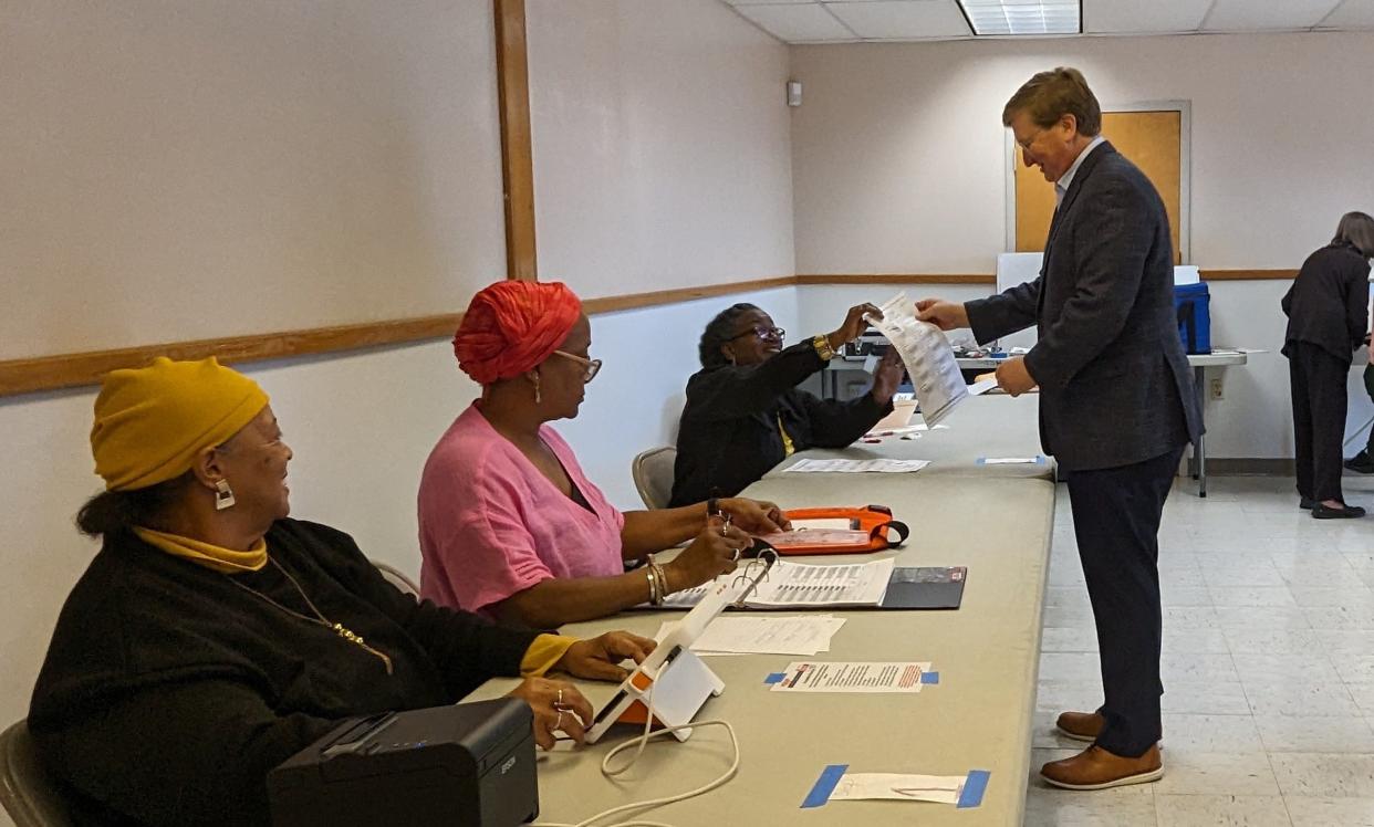 Gov. Tate Reeves receives his ballot from poll worker Joyce Lewis after he and his wife Elee arrived at the U.S. Military Entrance Processing Station in Jackson, Miss, to vote in the general election Tuesday. Nov. 7, 2023.