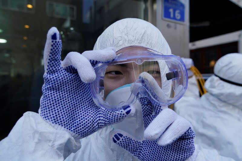 An employee from a disinfection service company wipes moisture from his goggles as he sanitizes a shopping district in Seoul