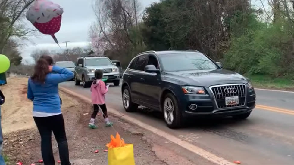 Image of girl celebrating birthday with neighbour's driving by with presents and balloons under COVID-19 lockdown