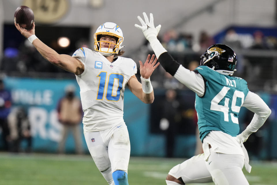 Los Angeles Chargers quarterback Justin Herbert (10) throws under pressure by Jacksonville Jaguars defensive end Arden Key (49) during the second half of an NFL wild-card football game, Saturday, Jan. 14, 2023, in Jacksonville, Fla. (AP Photo/Chris O'Meara)