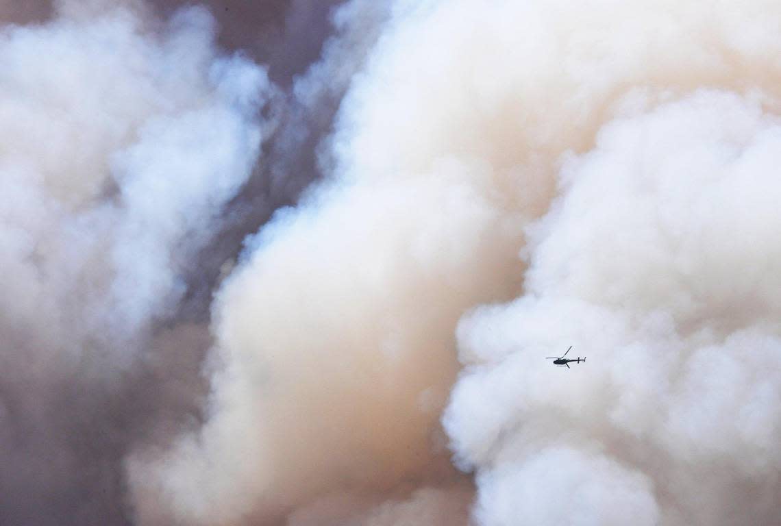 A helicopter flies through a giant plume of smoke as the Washburn Fire continues to burn near Wawona in Yosemite National Park Monday, July 11, 2022.