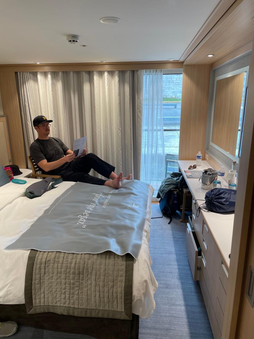 sarah kuta's partner sitting on bed on viking skaga stateroom