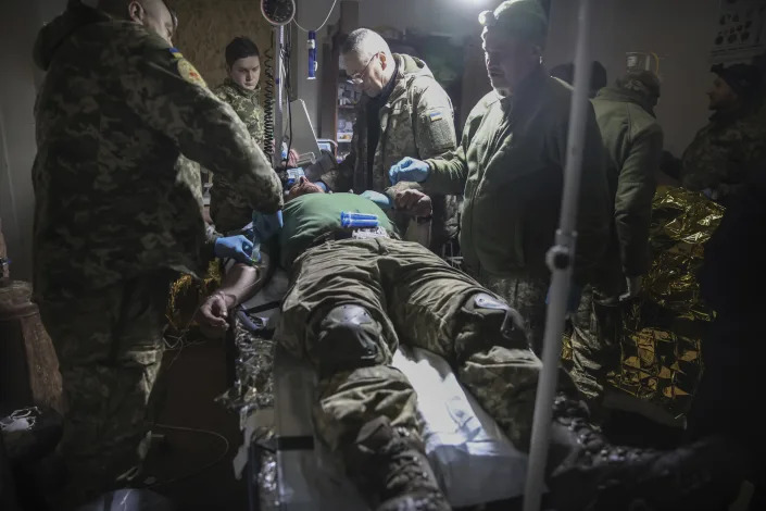 Medics give the first aid to a wounded Ukrainian soldier near Bakhmut, the site of the heaviest battles with the Russian troops, Donetsk region, Ukraine, Monday, Feb. 27, 2023. (AP Photo/Yevhen Titov)