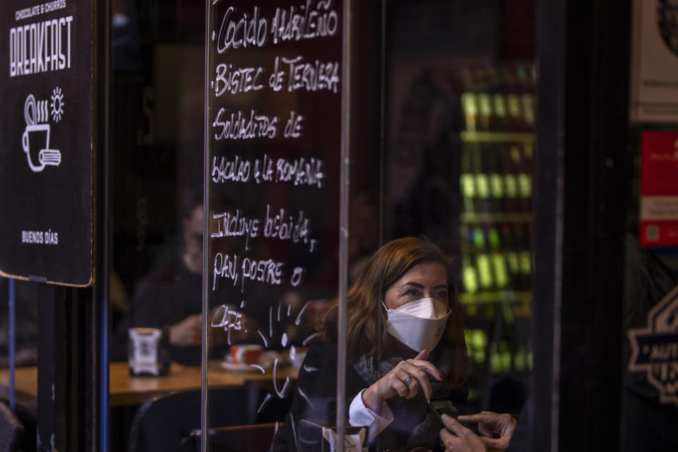 A woman wearing an FFP2 face mask to curb the spread of COVID-19 chats with a woman in a coffee bar in Madrid, Spain, Wednesday, Jan. 12, 2022. Italy, Spain and other European countries are re-instating or stiffening mask mandates as their hospitals struggle with mounting numbers of COVID-19 patients. (AP Photo/Manu Fernandez)