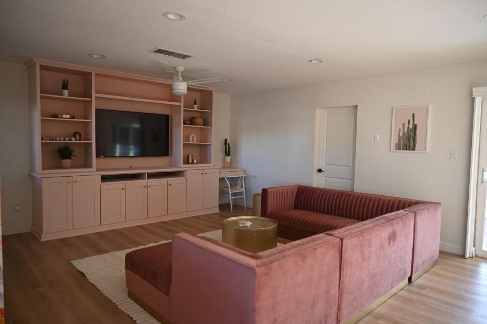 A living room with a pink built-in bookcase and matching pink couch.