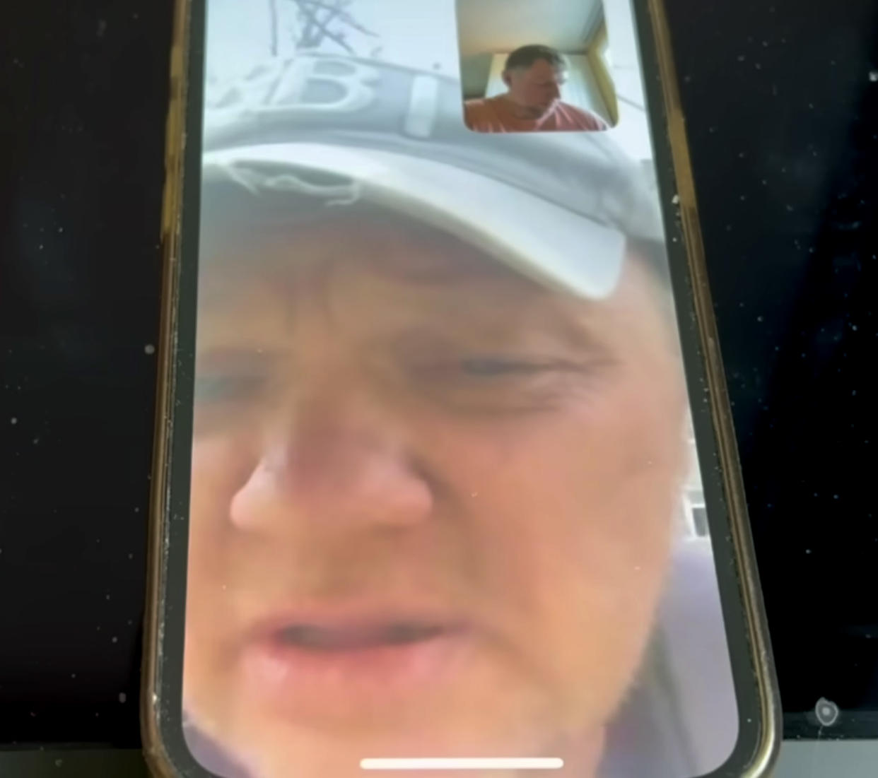 Alexei Savichev, wearing a cap, appears on a cellphone recording of a phone call with a small picture of Vladimir Osechkin in the corner.