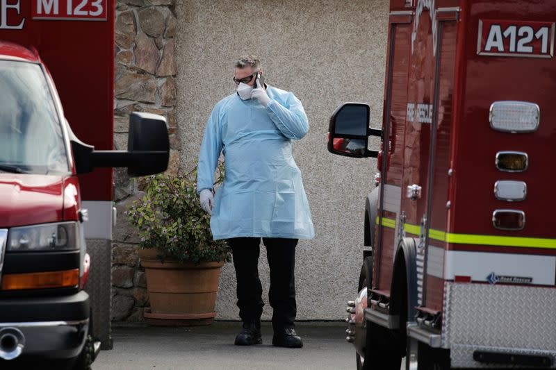 A medic talks on the phone while others transport a patient to an ambulance at the Life Care Center of Kirkland, the long-term care facility linked to several confirmed coronavirus cases in the state, in Kirkland