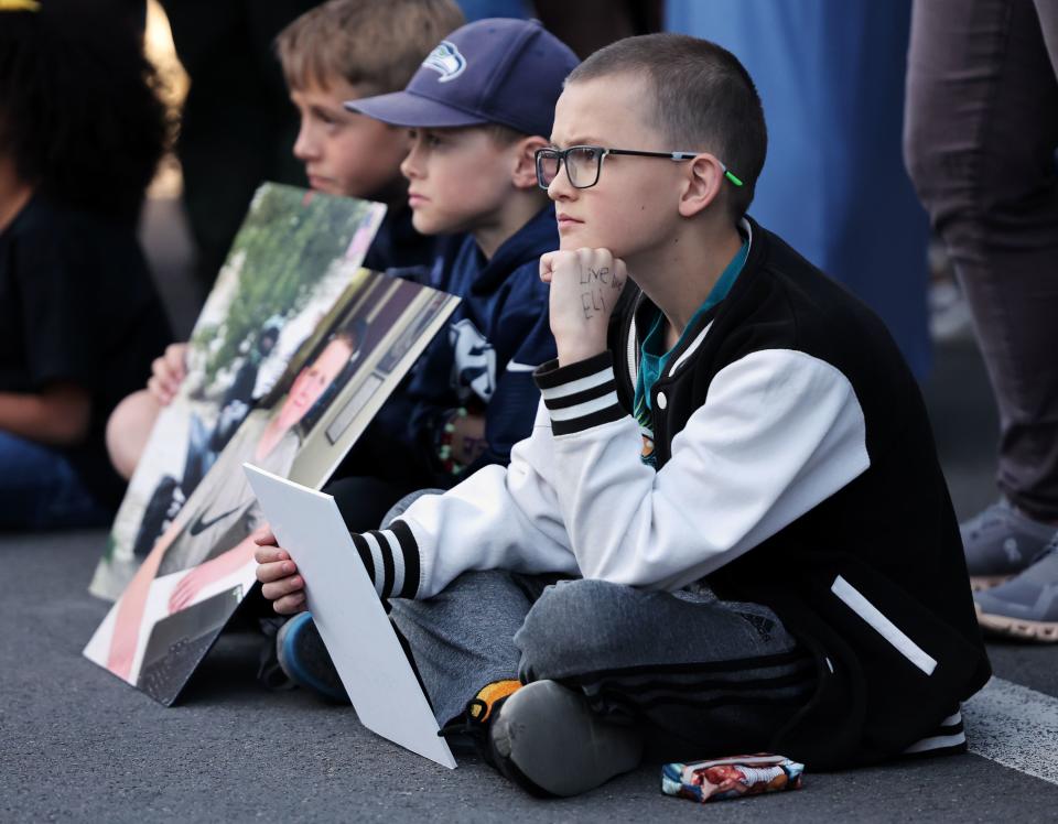 Kids hold photos of Eli Mitchell as they join a large group of people gathered on Wednesday, April 26, 2023, in West Jordan at 9000 South and 1510 West where 13-year-old Eli was killed by a drunk driver one year ago. | Scott G Winterton, Deseret News